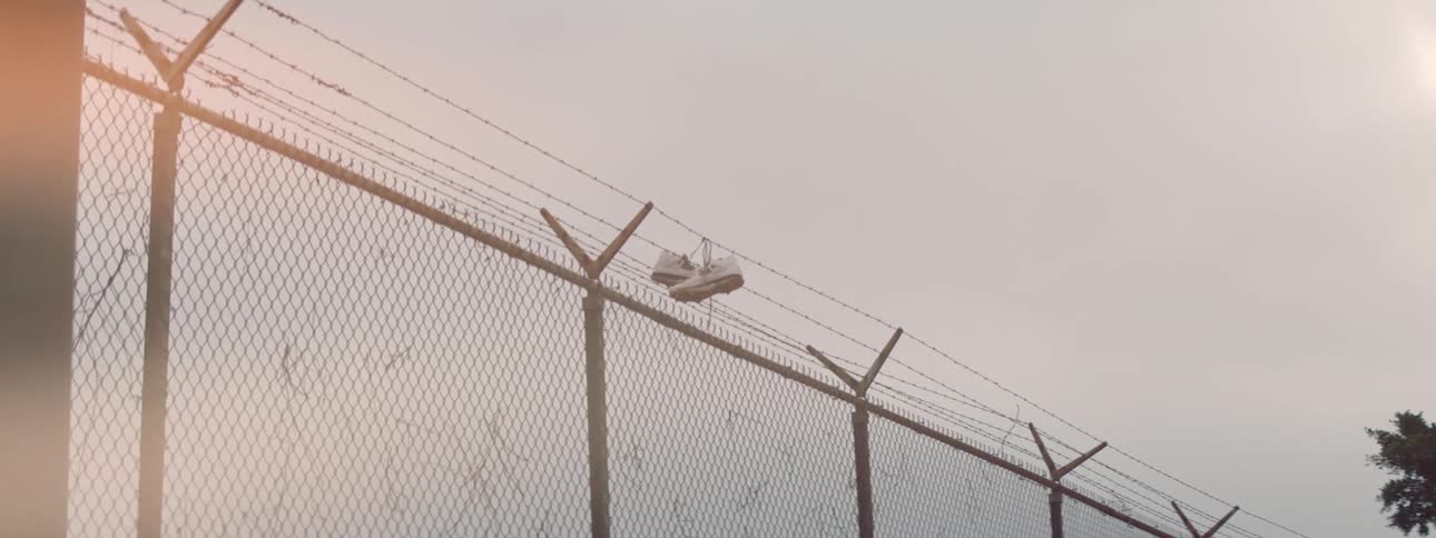 White tennis shoes hanging from barbed wire on top of chain link fence