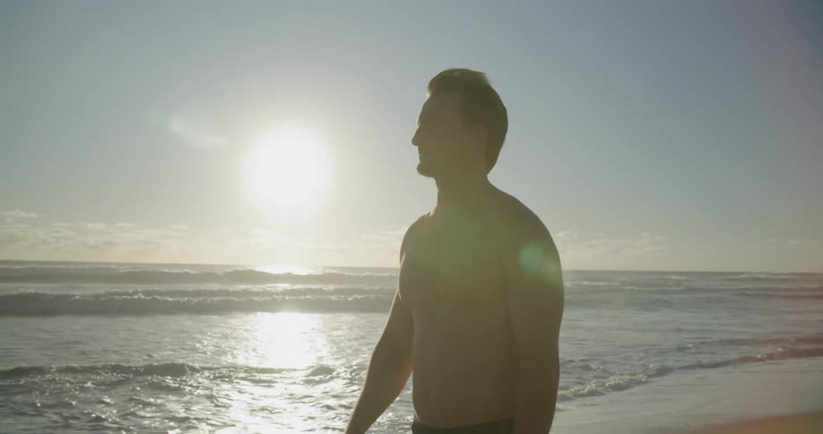 A man walks by himself on a quiet beach by the ocean water