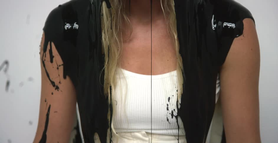 A woman with black paint being dumped on her