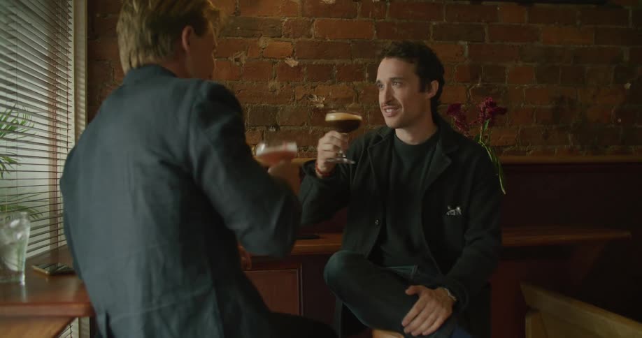 Two men in a room sitting talking and drinking