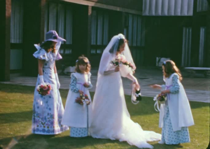 A bride holds her flowers as her mother and flower girl fix her train