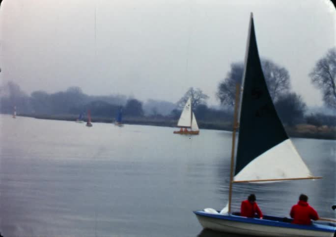 People are riding in little row boats on a lake in the fall