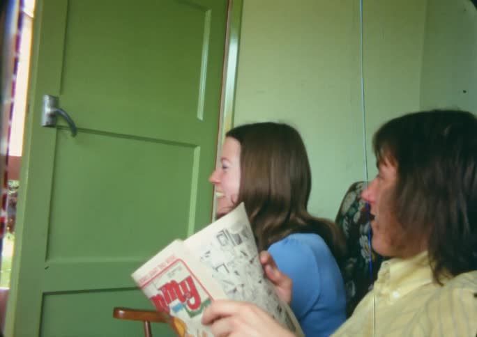 Young couple sitting in a room at home talking and looking at the camera