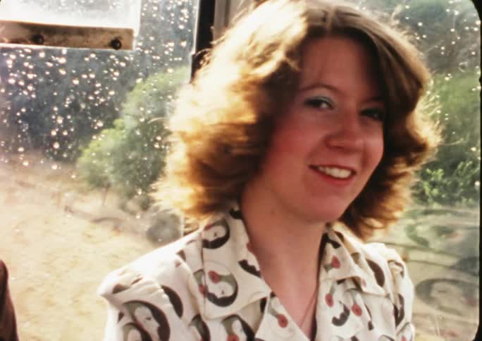 Vintage footage of a woman sitting on a bus smiling and turning her head to talk to someone