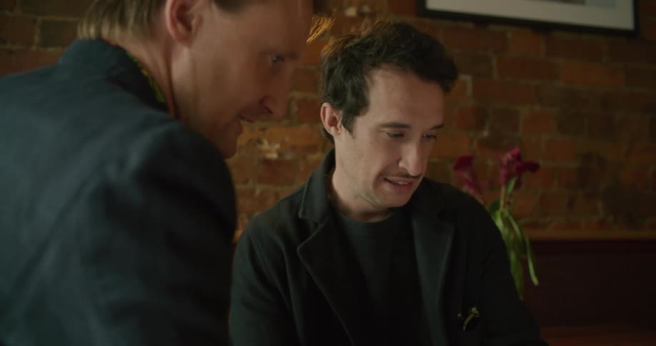 Two man looking at a smartphone in a restaurant