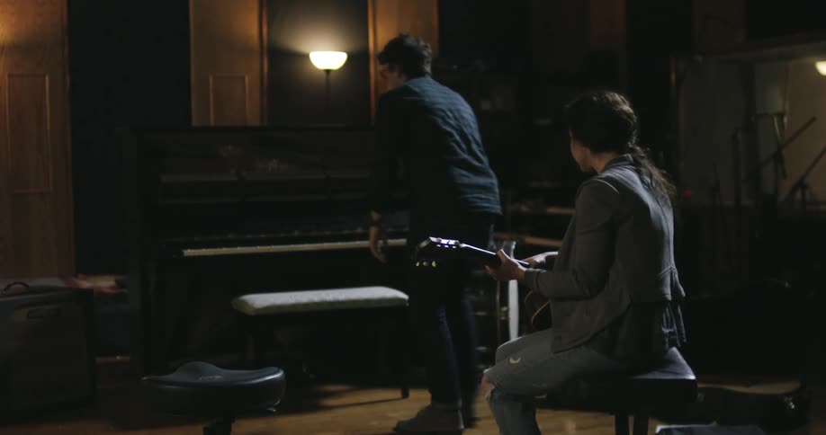 Man sets down guitar and sits down at a piano