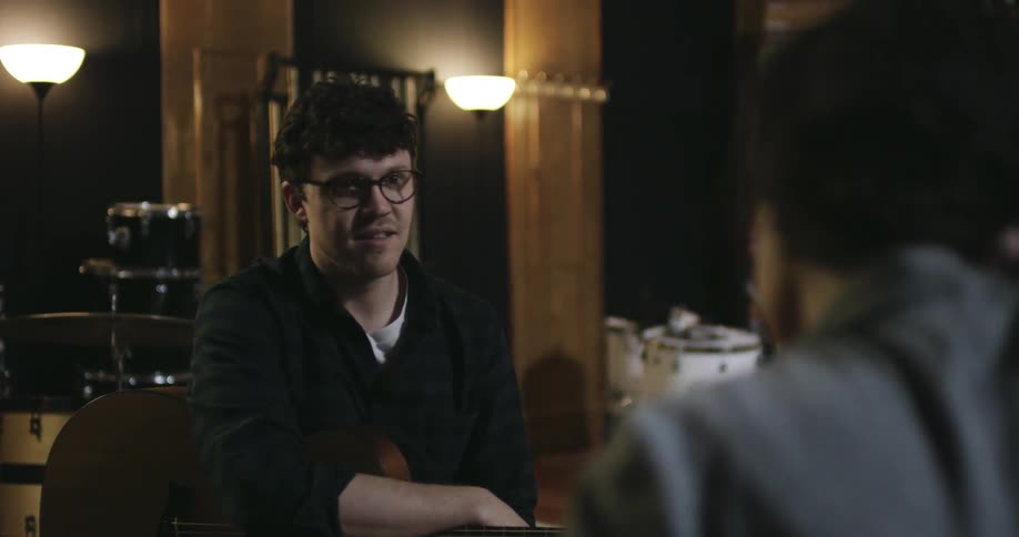 Man and woman sitting with guitars talking and smiling
