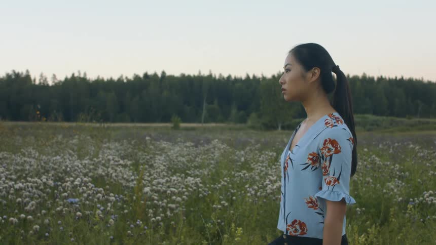 A woman is walking outdoors in a field of grass