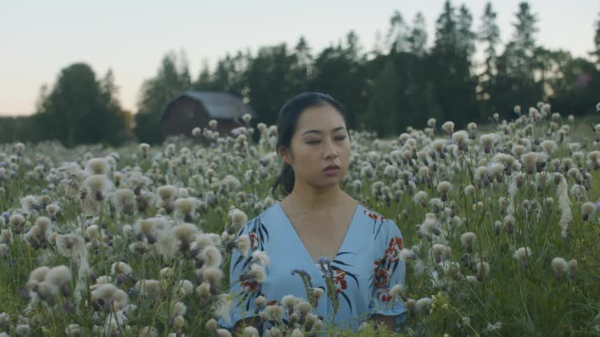 Woman standing in a field of flowers looking around