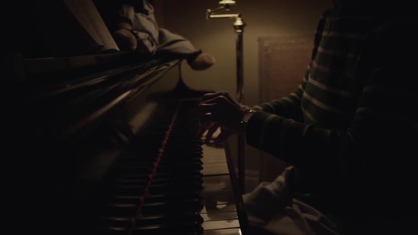 A person is playing a piano in a dark room