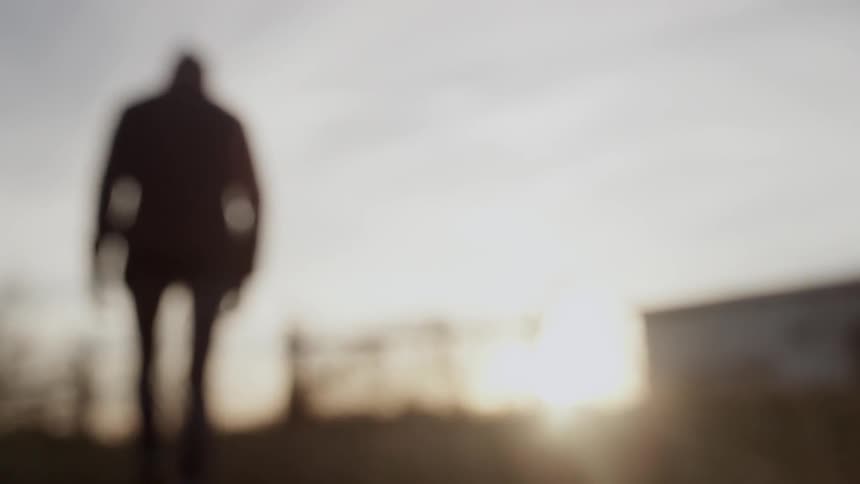 Man crosses a field at sunset