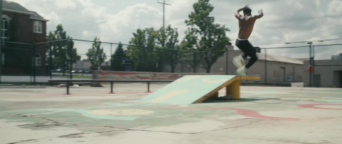 A male teenager rollerblades over a ramp in a park