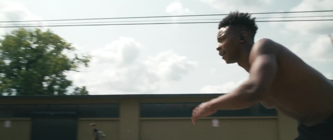 Strong muscular shirtless young man riding inline skates on the streets of a city
