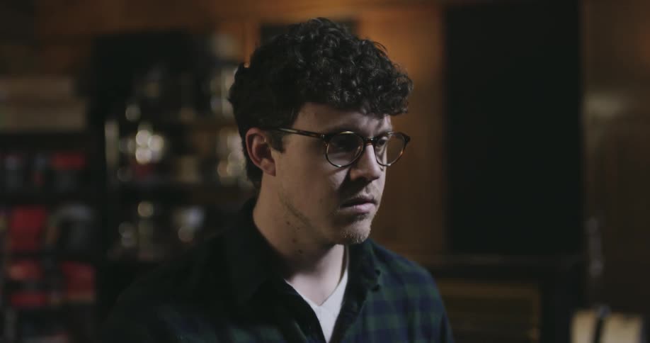 A man wearing glasses turns his head down