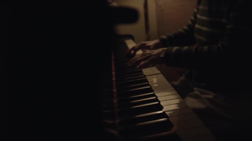 A person is playing a piano in a dark room