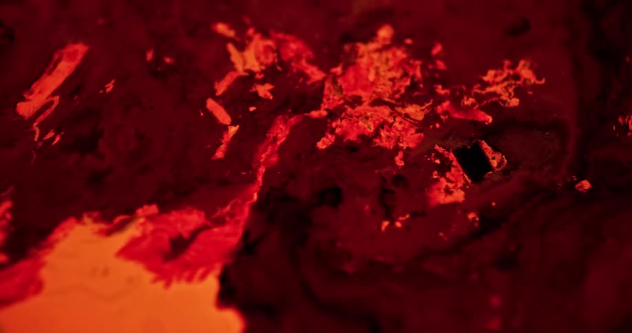 Bright colorful red ink flowing over a surface forming abtract chaotic patterns