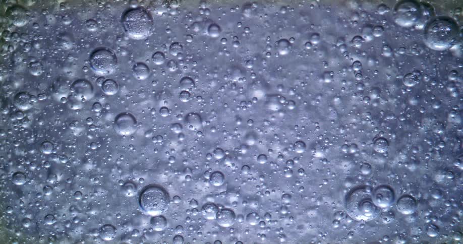 Various sized bubbles rise through metallic blue liquid