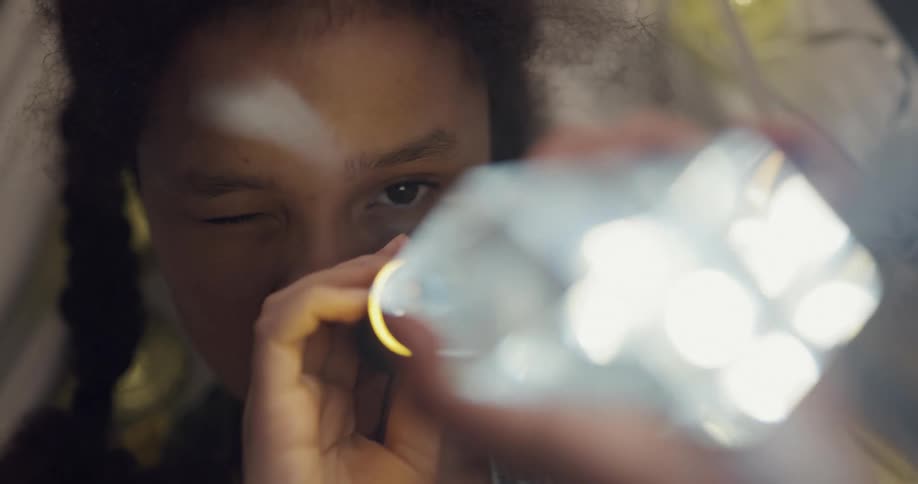 Black woman uses a flashlight to examine a piece of crystal