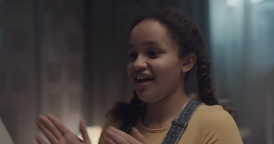 A girl plays a clapping game with another person in a room in a house