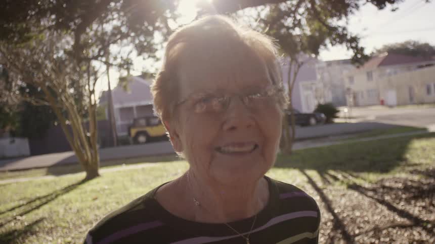 An elderly woman smiling while standing outdoors