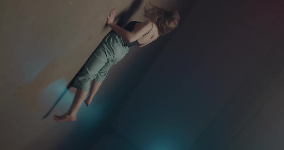 A woman is dancing in a room with concrete floors