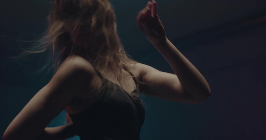 Woman dancing alone at a dark room