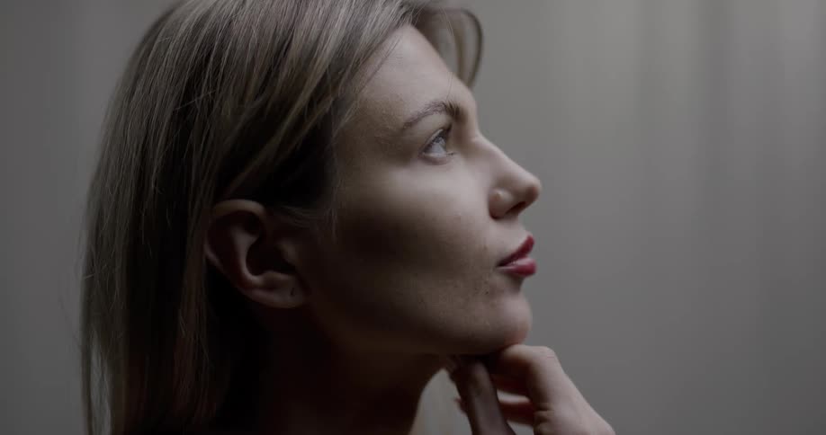 A womans face in profile with her hand resting on her chin