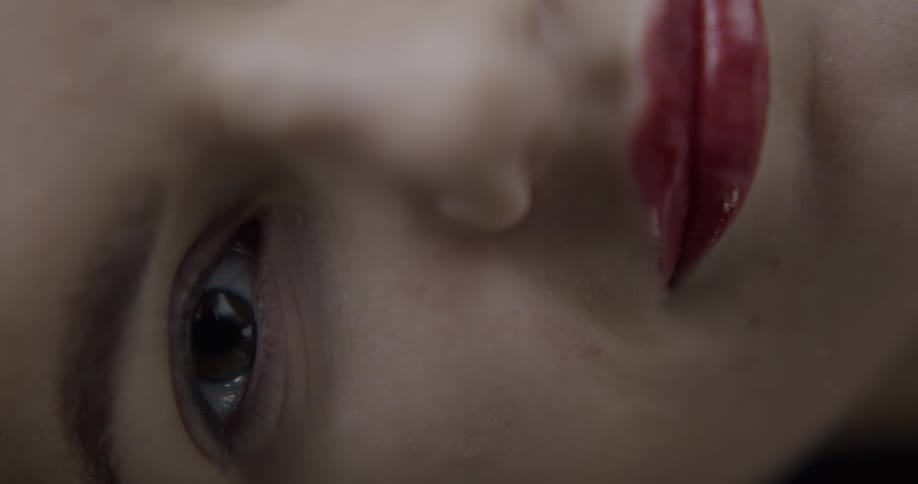 Sideways close up of a young womans face looking at the camera