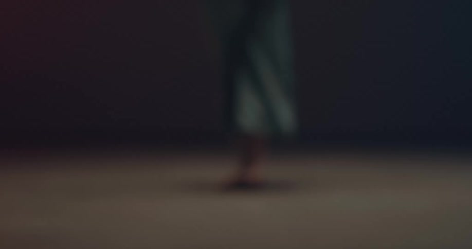 Young woman wearing a dress dancing barefoot in a dimly lit stage