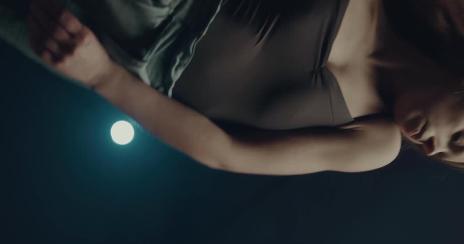 A woman dances in a dimly lit room