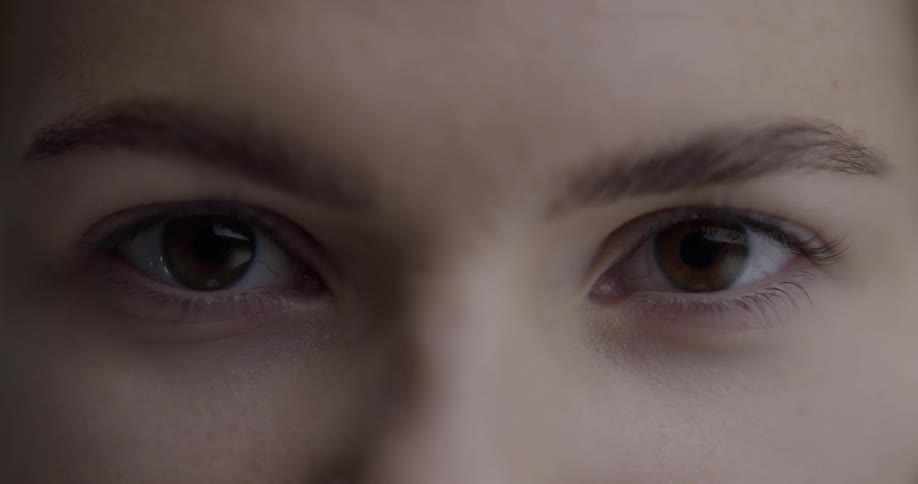 Close up of a womans brown eyes opening and closing