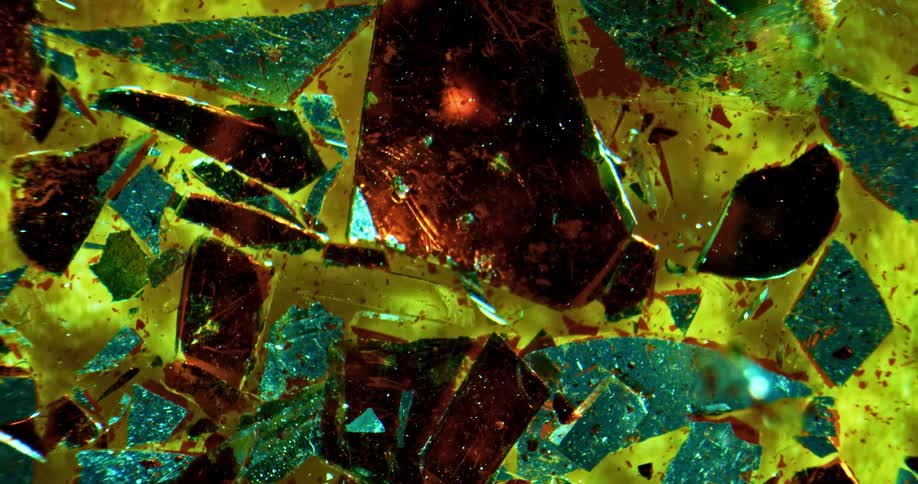 Shards of colored glass float against a yellow backdrop sparkling and shimmering