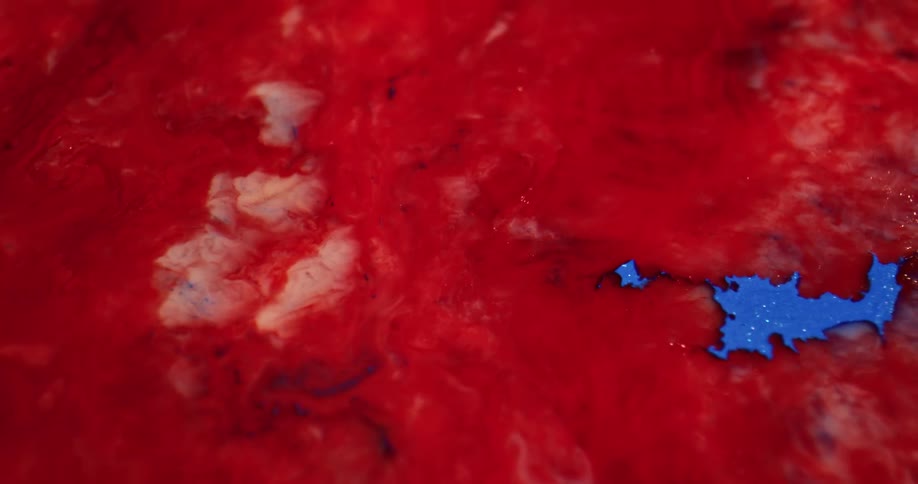 Close up of a red liquid with a splash of blue inside of it