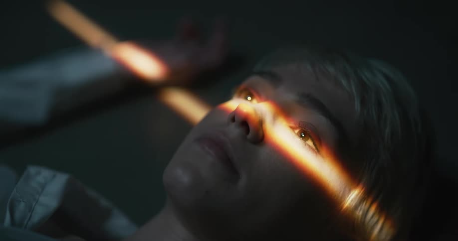 A young woman lying on the floor with a strip of light going across her eyes