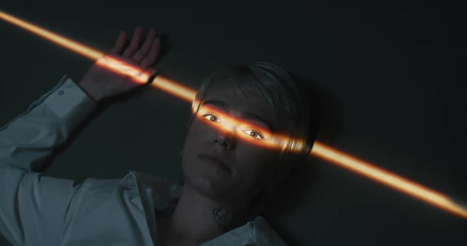 A woman laying on the floor with a light shining on her eyes