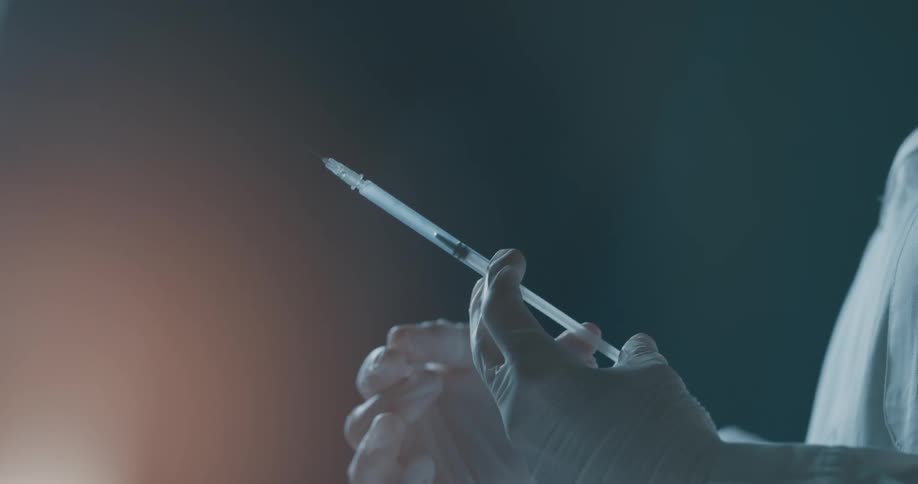 A doctor flicks and sprays a needle