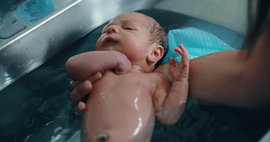 A newborn is being washed in the sink water