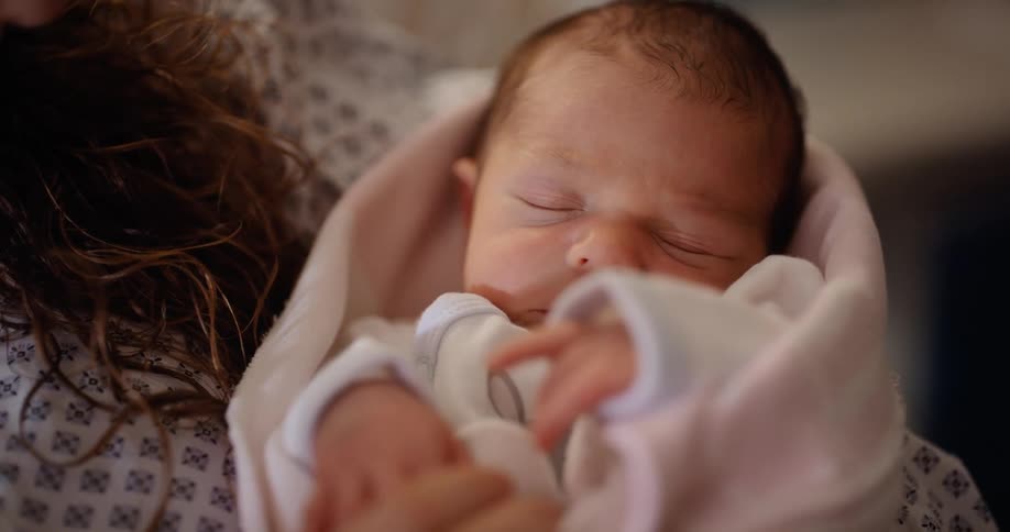 A newborn baby being held by their mother in a hospital