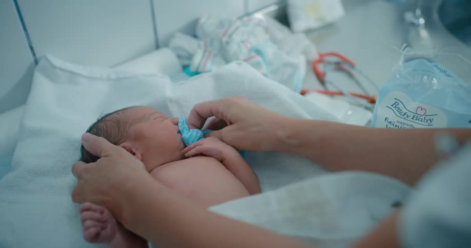 Person is wiping off a babys face with water and a blue towel