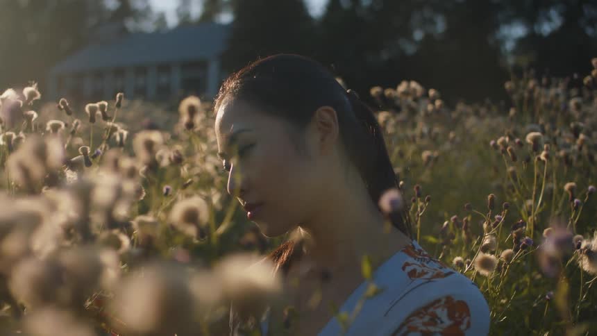 A woman is standing outdoors in a field of flowers