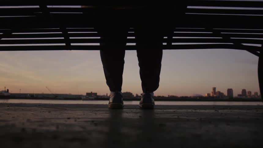 A person is sitting on a bench at sunset