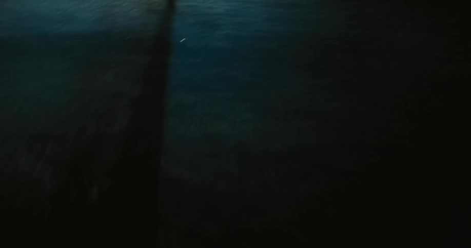 A person runs quickly on grass towards a car in foggy conditions at night