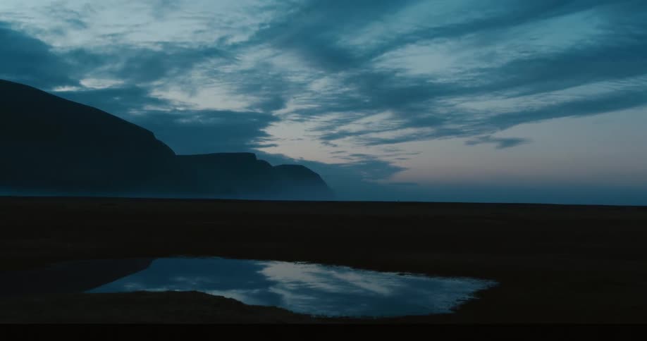 A body of water reflecting the sky with mountains in the distance