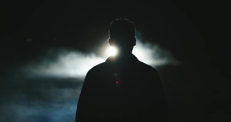 A man races towards a parked vehicle at night