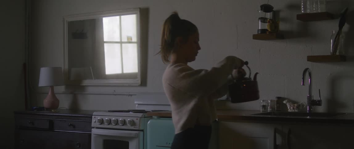 Young woman takes a kettle out of the fire in the kitchen at home