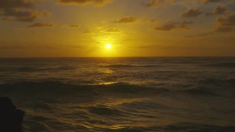 Beautiful sunset in an orange sky as ocean waves roll in