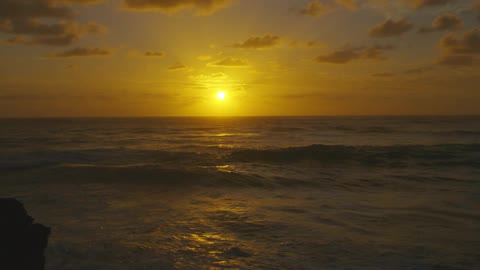 Landscape of sun setting against an ocean and clouds