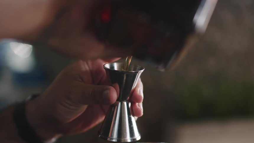 A person pouring alcohol into a measuring glass