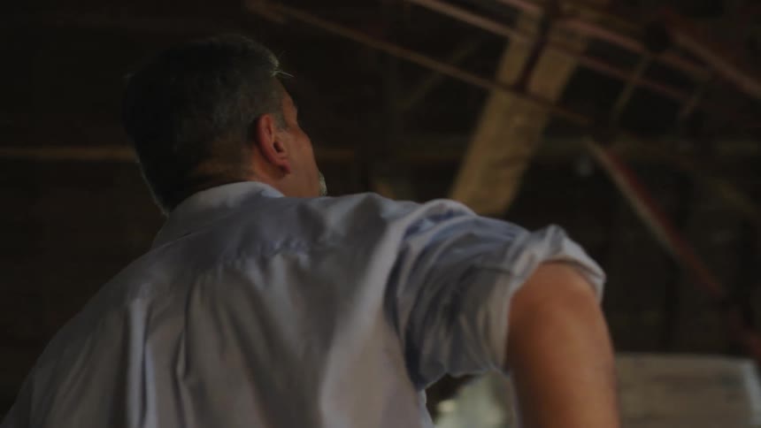 Man standing inside a barn looking at the ceiling