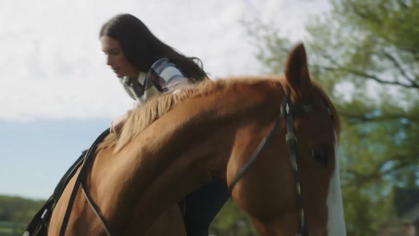 A woman on a ranch gets on to her horse